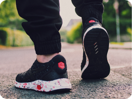 Jemand steht in schwarzen Turnschuhen auf der Straße, nur die Füße des Mannes sind zu sehen.